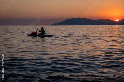 Stand up paddle boarder SUP silhouette on the water of the sea. Evening, sunset at sea © Alexey Oblov