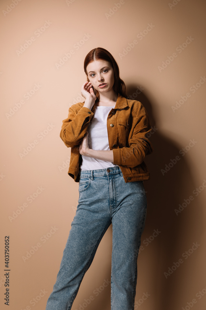 Girl in jeans and a brown jacket posing on a beige background Stock ...