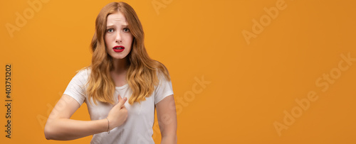 Indignant woman points at herself with for finger, has dissatisfied expression. Copy space