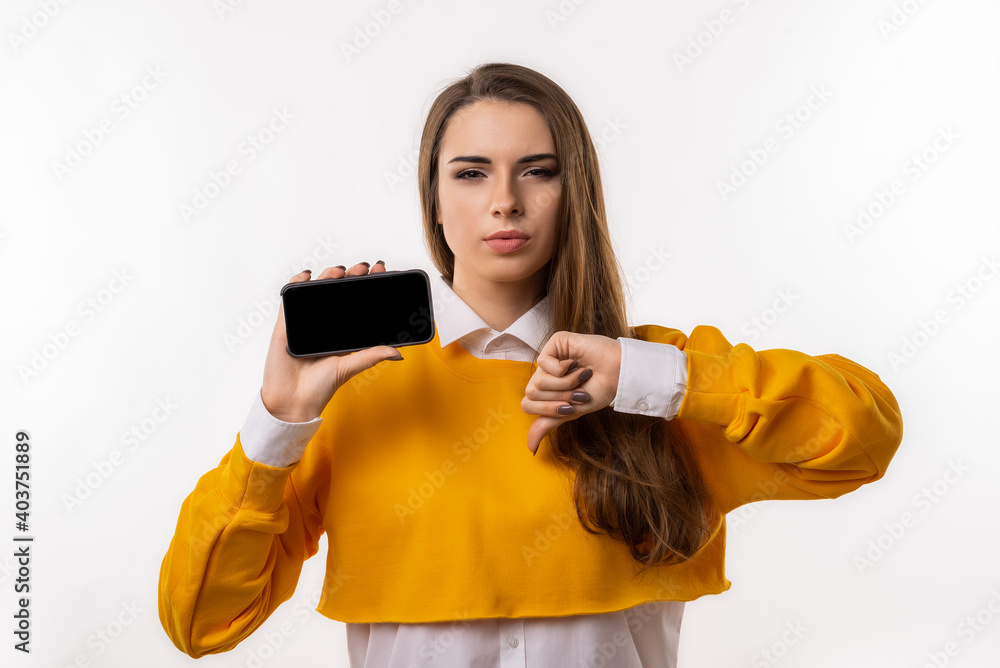 Pretty young brunette woman in casual clothes is showing smartphone blank screen in her hand Pretty young brunette woman in casual clothes is showing smartphone blank screen in her hand