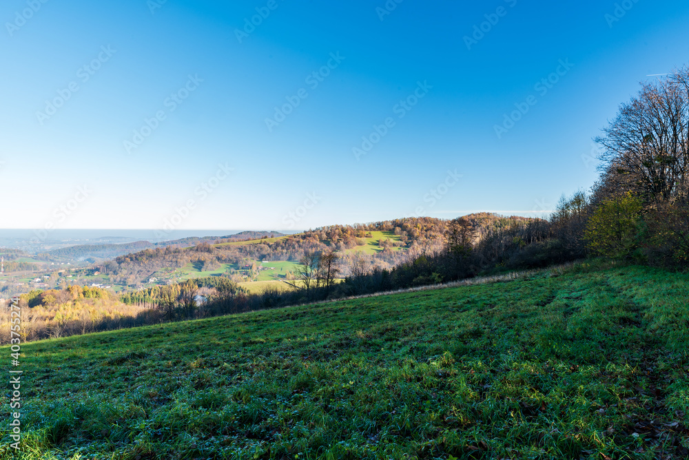 Late autumn rolling landscape with meadows, smaller hills, forest and clear sky from Wrozna hill in Beskid Slaski mountains on polish - czech borders