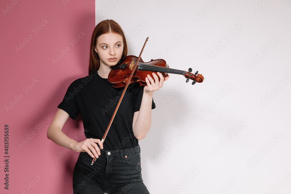 Girl in black plays violin on pink background Girl in black plays violin on pink background