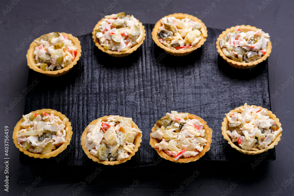 Salad tartlets with pineapple and shrimps on a black wooden board on a gray concrete background. Salad tartlets with pineapple and shrimps on a black wooden board on a gray concrete background.