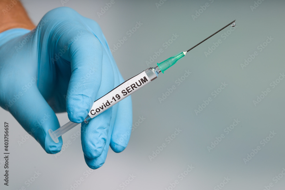 Close up of doctor's hand in medical gloves with a syringe with Covid-19 vaccine ready for injection Close up of doctor's hand in medical gloves with a syringe with Covid-19 vaccine ready for injection