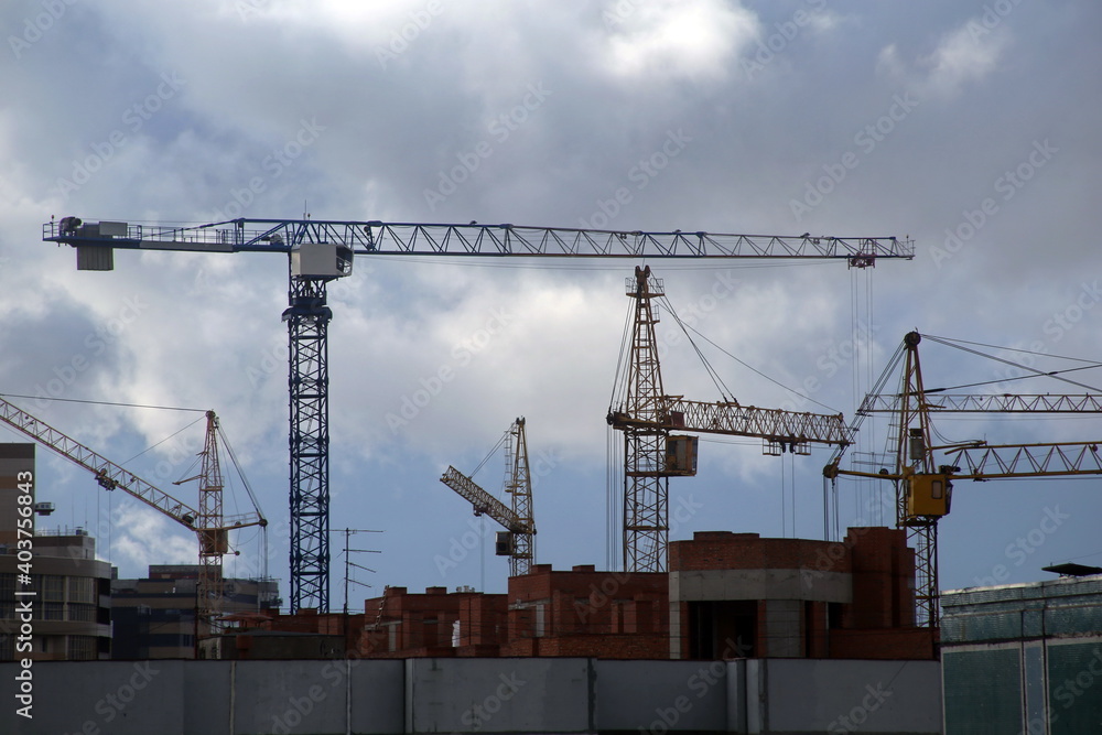 Construction cranes against the background of the evening sky. City. Construction of houses. Tower crane. Lifting crane. Civil engineering Construction cranes against the background of the evening sky. City. Construction of houses. Tower crane. Lifting crane. Civil engineering