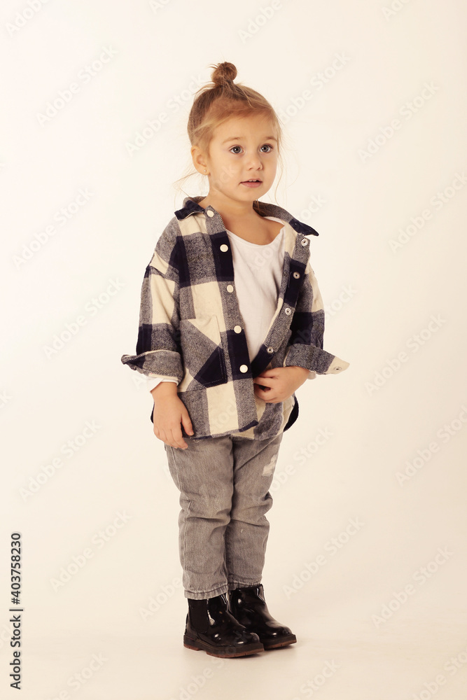 cute little blond baby girl in black boots, jeans, checkered shirt with copy space isolated on white cute little blond baby girl in black boots, jeans, checkered shirt with copy space isolated on white