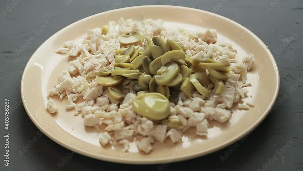Chopped champignons are poured into a plate with chopped chicken fillet. Medium plan Chopped champignons are poured into a plate with chopped chicken fillet. Medium plan