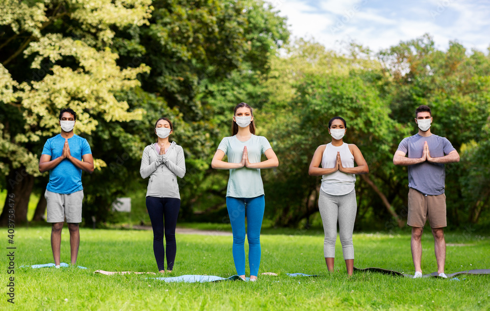 fitness, sport and healthy lifestyle concept - group of happy people wearing face protective medical mask for protection from virus disease doing yoga at summer park fitness, sport and healthy lifestyle concept - group of happy people wearing face protective medical mask for protection from virus disease doing yoga at summer park