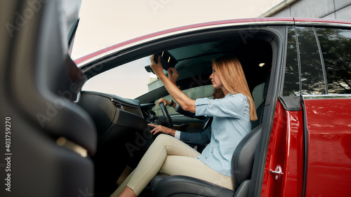 Young woman examining interior while sitting on passenger seat