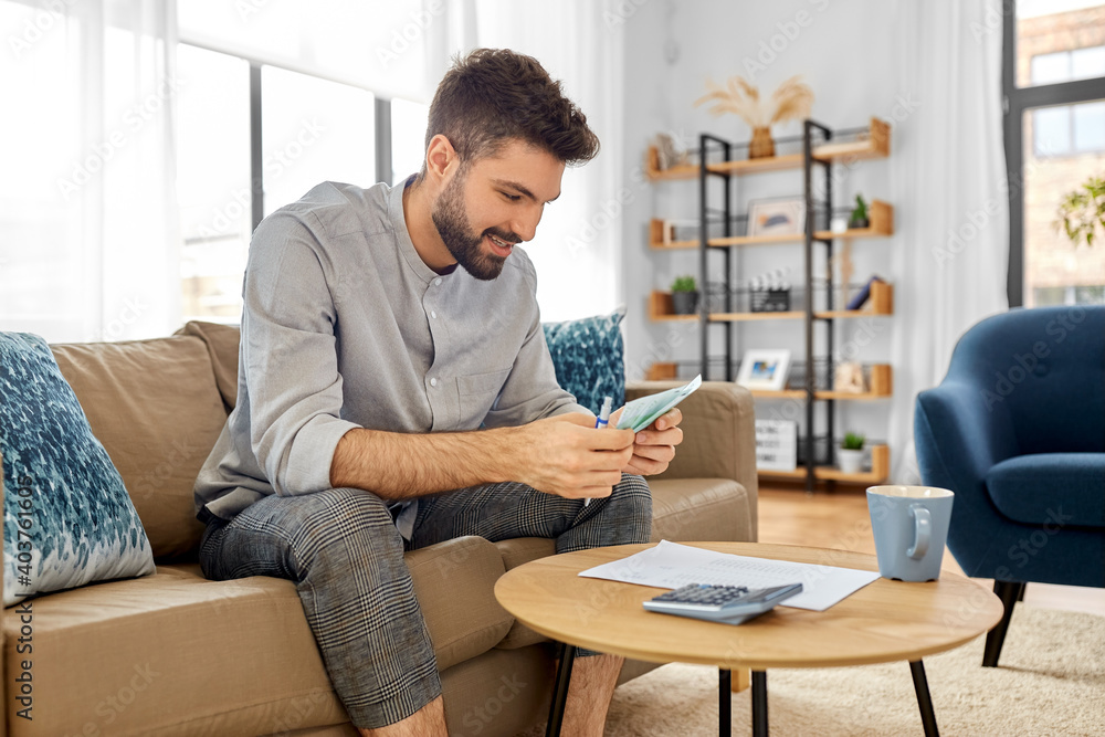 business, finances, accounting and people concept - man with money and calculator filling papers at home business, finances, accounting and people concept - man with money and calculator filling papers at home