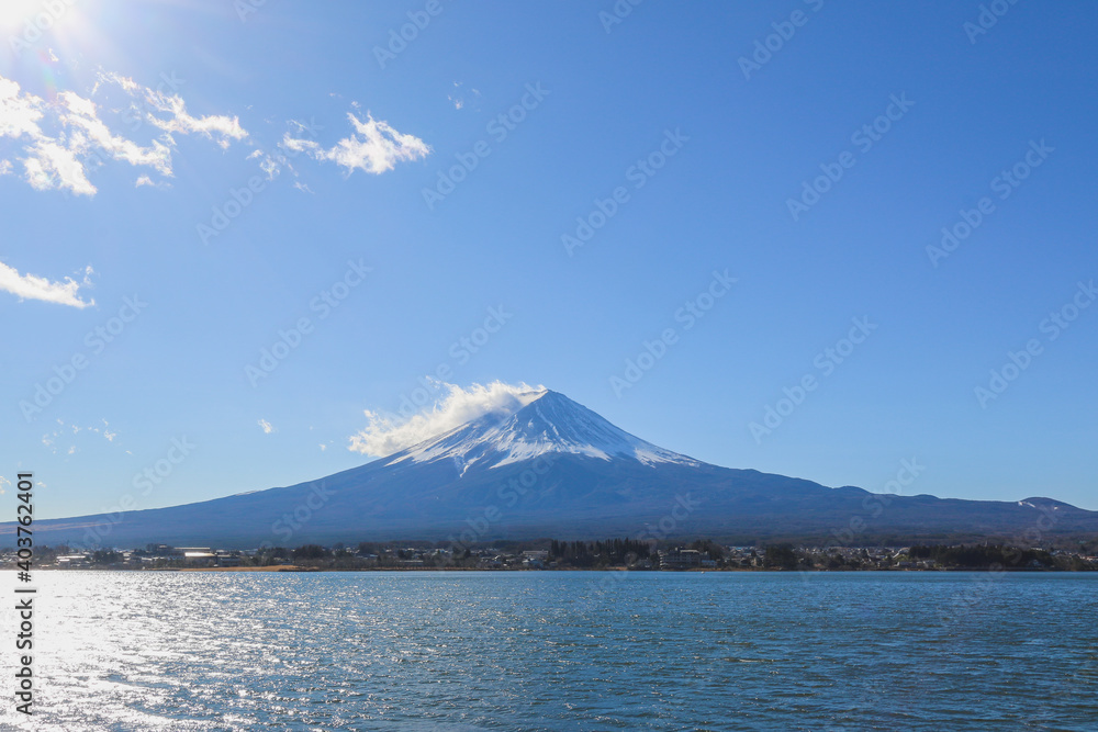 Mount Fuji is in front of a lake. There is a blue sky as the copy space background.