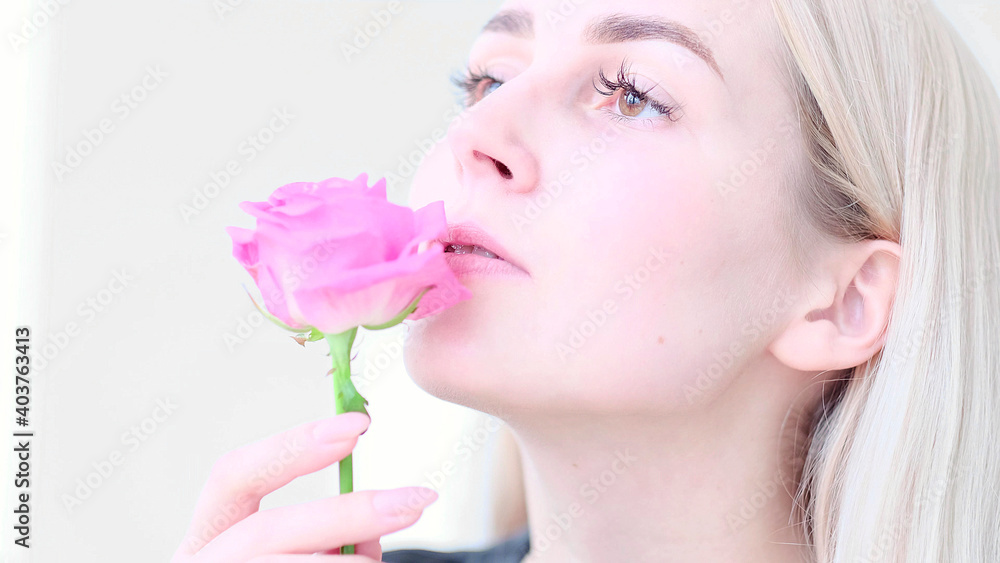 Beautiful young woman with delicate rose flower. Girl clean fresh skin touching her face in flowers. soft focus, selective focus