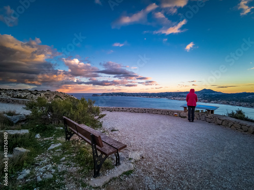 Empty wooden bench and tourist over the bay