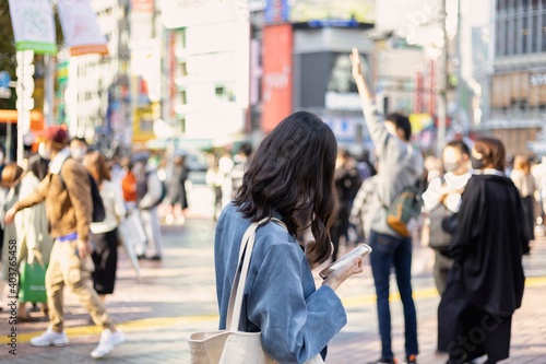 渋谷駅前でスマートフォンを見る若い女性