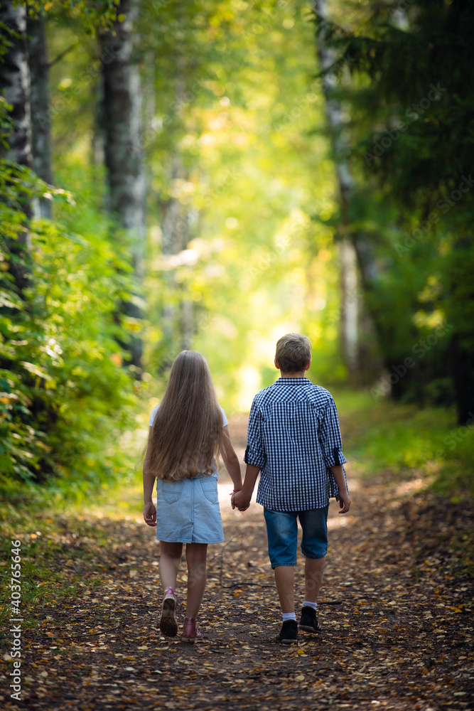 Beautiful boy and girl walking in the beautiful summer forest