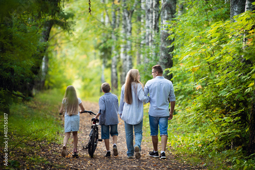 Rear view of family walking along autumn path in a park or forest © romankosolapov