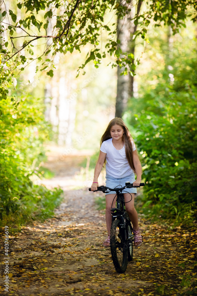 Children girl riding bicycle outdoor in forest smiling. Children girl riding bicycle outdoor in forest smiling.
