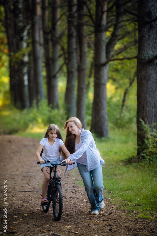 Fototapeta premium Happy mother teaches his daughter to ride a bike