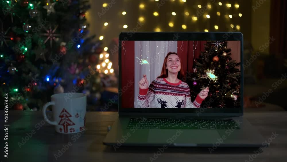 Happy woman with sparklers on a videocall, she is happy and wishing a merry Christmas online Happy woman with sparklers on a videocall, she is happy and wishing a merry Christmas online