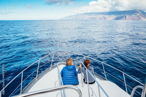 Couple enjoys the view of the coast of Tijarafe on the island of La Palma from the bow of a recreational boat, La Palma, Santa Cruz de Tenerife, Canary Islands, Spain, Europe.