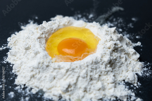 Egg breakage in white flour on a black background.


