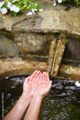 Fotografia Women's hands picking up clear water from a fountain to refresh themselves in po
