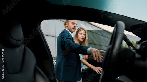 Happy young caucasian spouses examining car interior