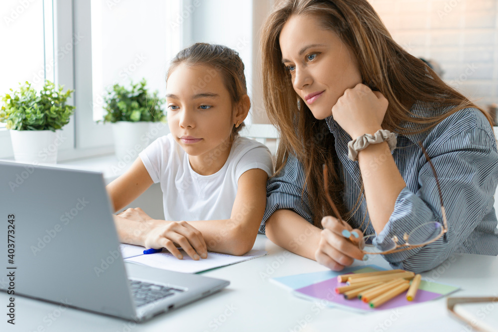 Mom helps her daughter with online homework - they looking to the laptop monitor. Mom helps her daughter with online homework - they looking to the laptop monitor.