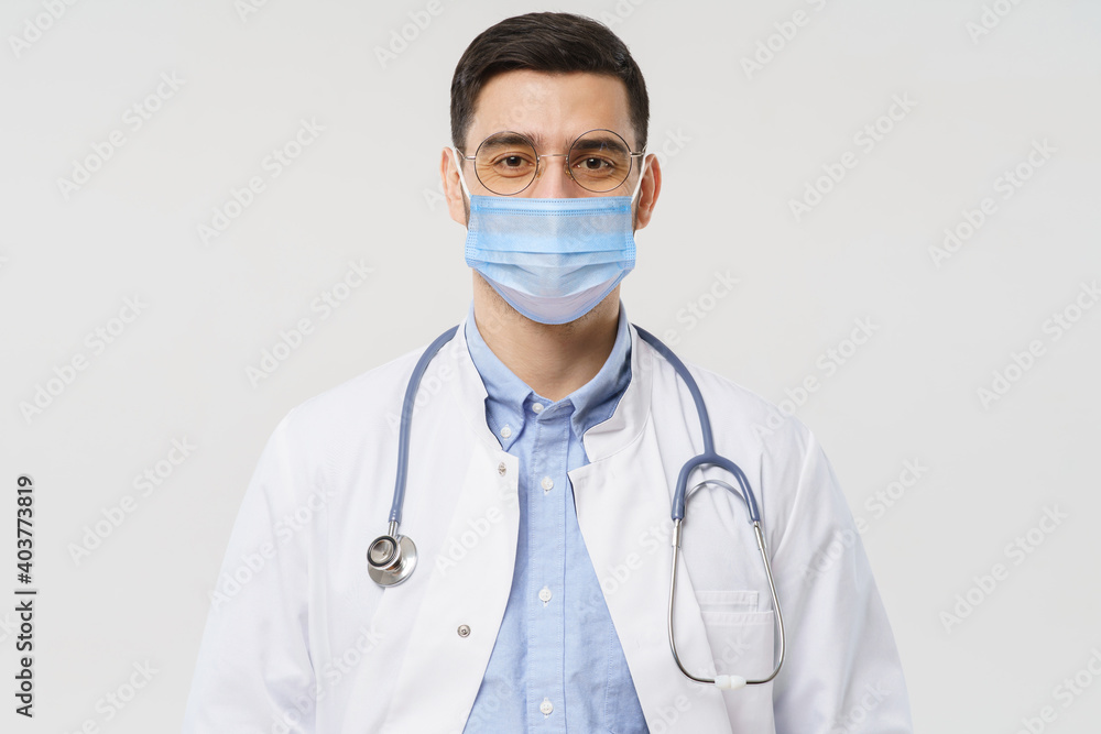 Close-up portrait of young doctor wearing medical mask and ready to help patients with coronavirus or covid virus, isolated on gray background Close-up portrait of young doctor wearing medical mask and ready to help patients with coronavirus or covid virus, isolated on gray background