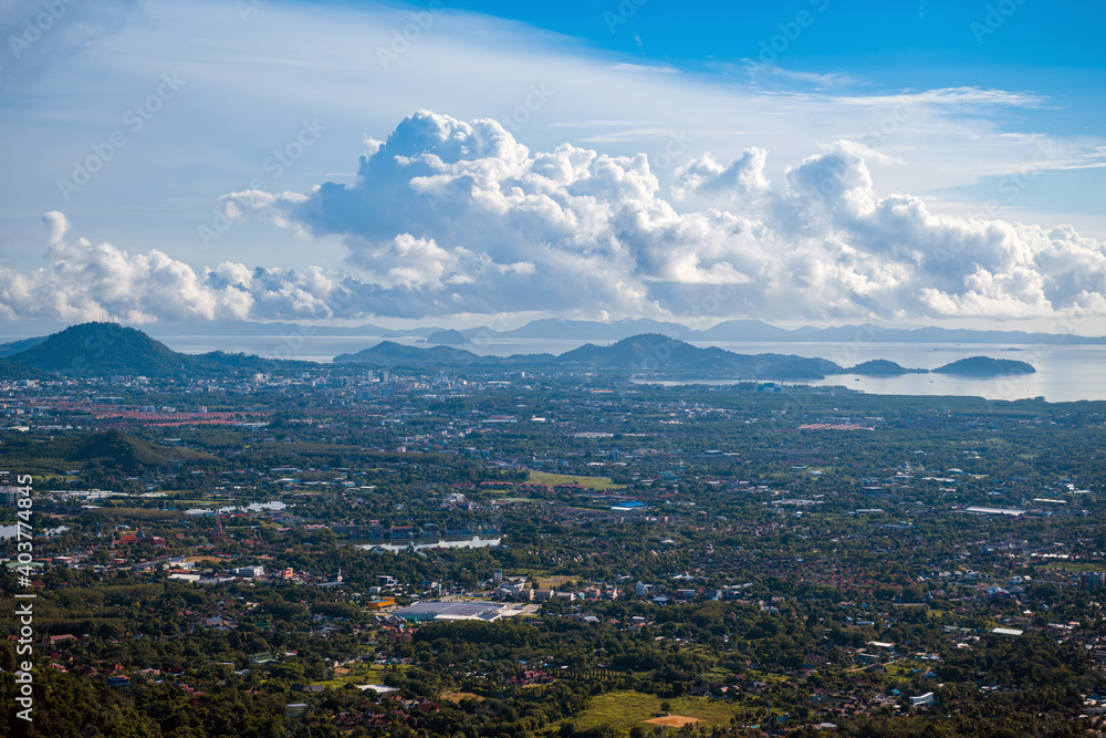 The landscape of the mountain ridge of Phuket and the Adaman Sea against the background of a blue sky with clouds.