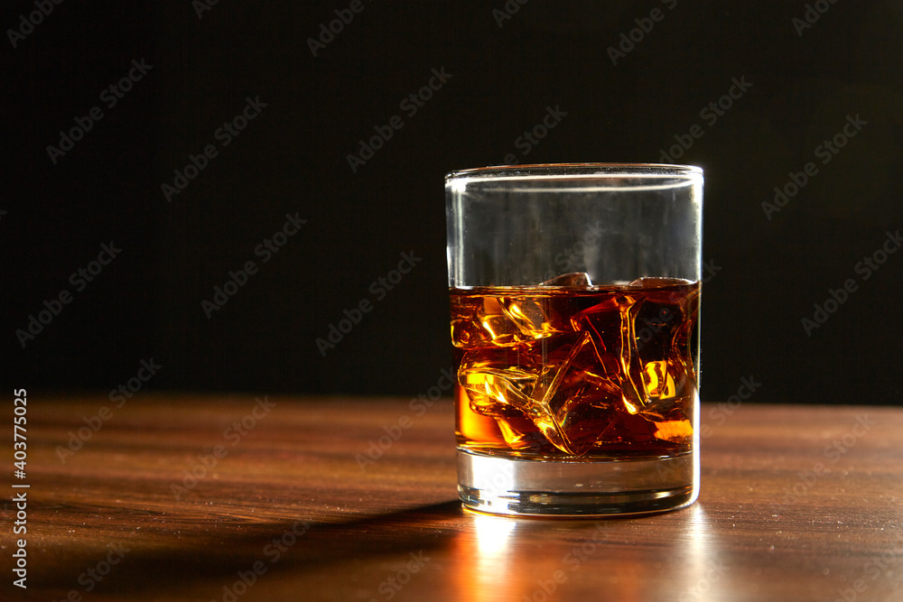 A Glass of whiskey on ice on wood table A Glass of whiskey on ice on wood table