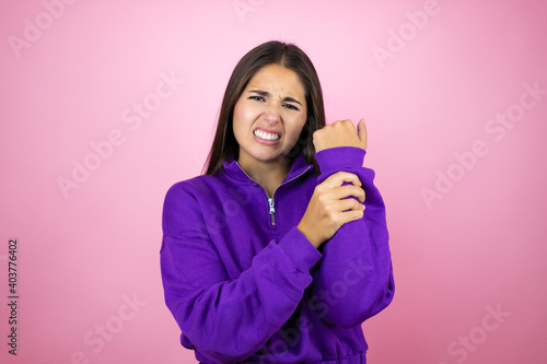 Young beautiful woman wearing sweatshirt over isolated pink background suffering pain on hands and fingers, arthritis inflammation