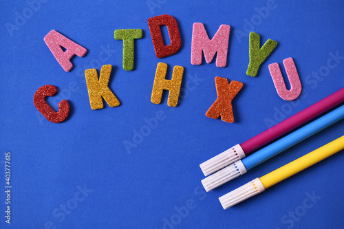 Random color letters with red blue and yellow pencils and magic markers on blue background