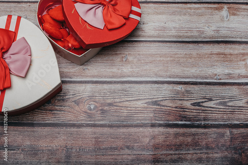 Valentine greeting card. Heart boxes with bows on a wooden table. Top view with copy space