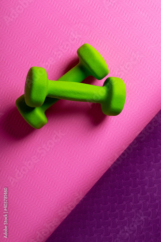Two green dumbbells on a yoga mat. Healthy lifestyle concept