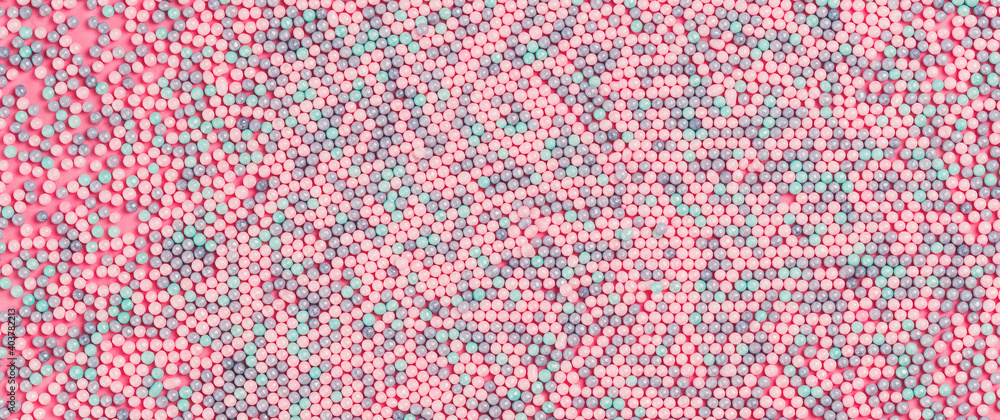 Colorful nonpareils cake candy sprinkles textured pattern background in flat lay. Party celebration or bakery concept. Pink color