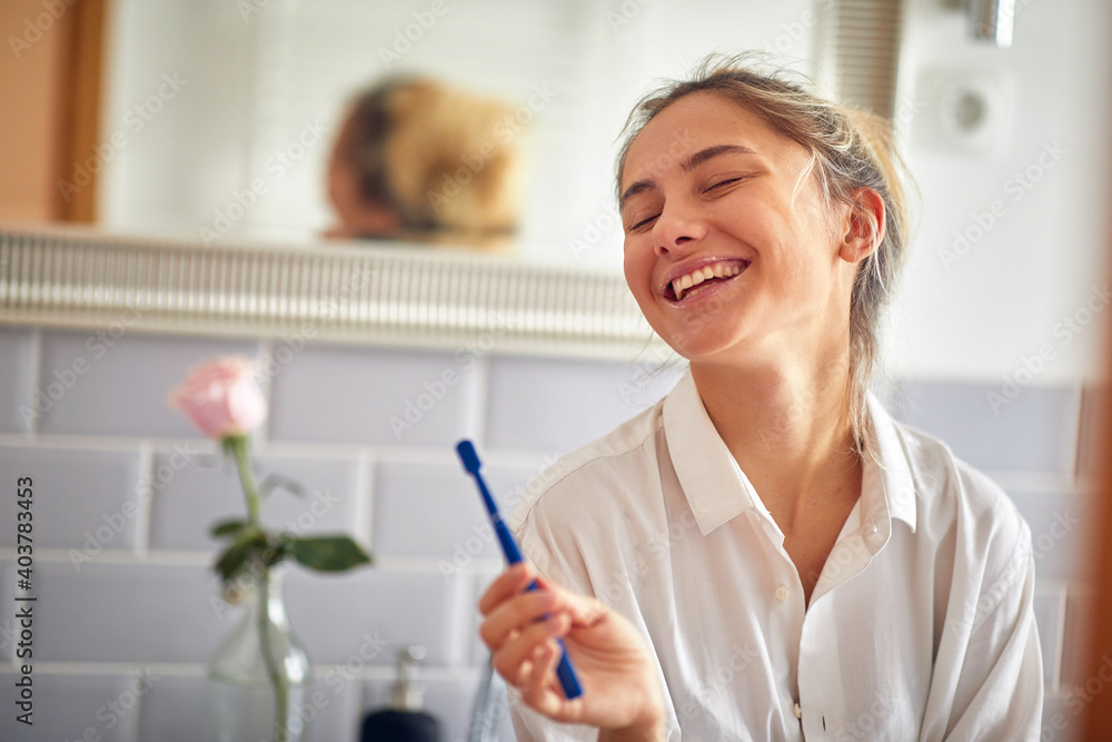 A young girl posing for a photo while brushing the teeth at the bathroom. Routine, morning, hygiene A young girl posing for a photo while brushing the teeth at the bathroom. Routine, morning, hygiene