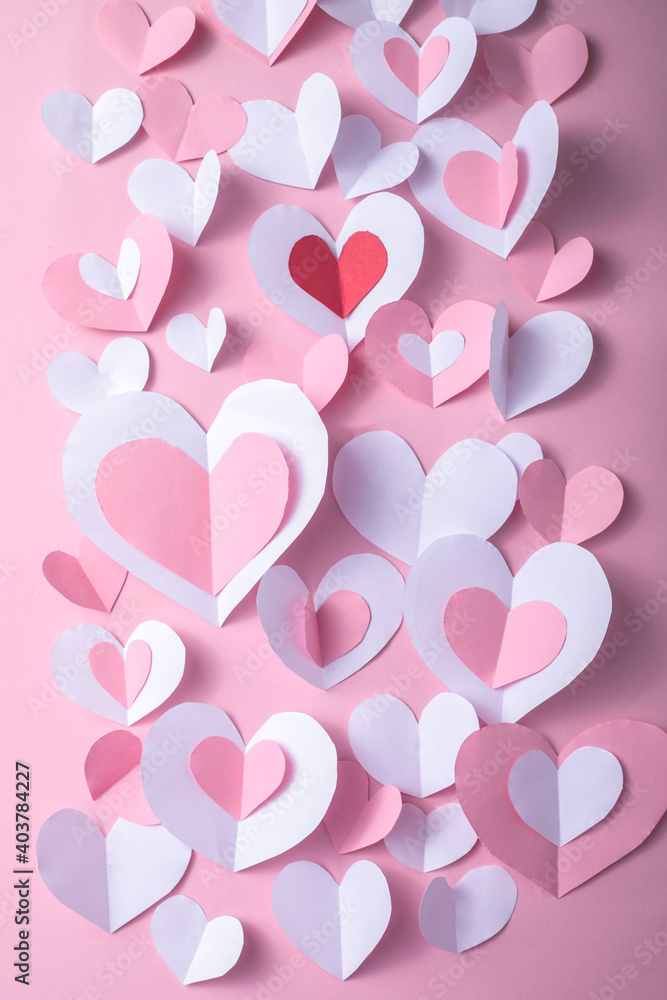 Valentine's Day festive background with pink and white paper hearts on a pink background for Valentines  holiday. Flatlay. Top view. Copyspace.