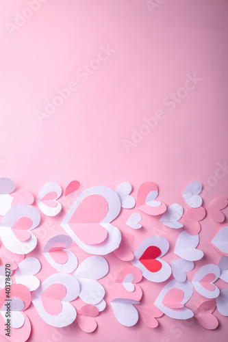Valentine's Day festive background with pink and white paper hearts on a pink background for Valentines  holiday. Flatlay. Top view. Copyspace.