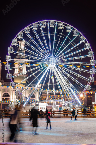 Kyiv (Kiev), Ukraine - January 6, 2021: A lot of people and children go ice skating outside near a big Ferris Wheel