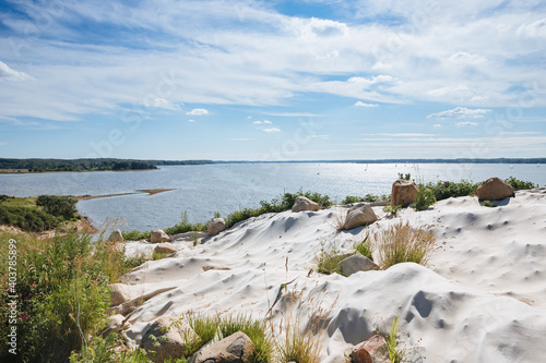 rock with sand and stones and blue lake in the background