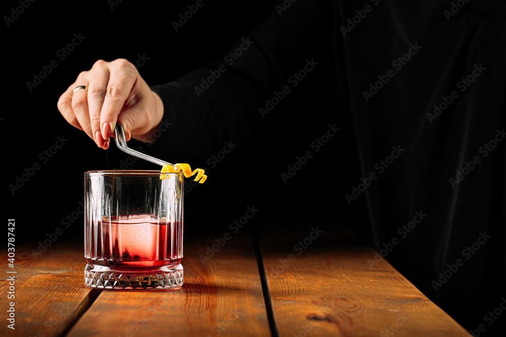 Side view on making negroni cocktail in old fashioned glass on the wooden table Side view on making negroni cocktail in old fashioned glass on the wooden table