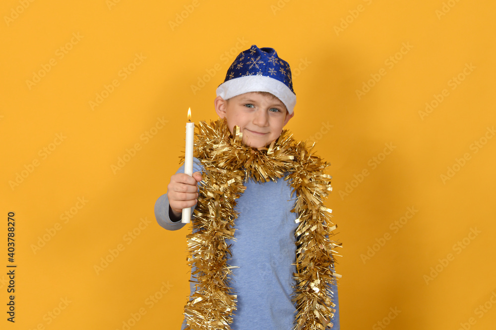 A cheerful child with a New Year's hat and rain stretched out his hand with a burning candle. A cheerful child with a New Year's hat and rain stretched out his hand with a burning candle.