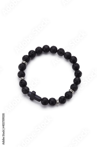 Detailed shot of black bracelet made of lava stone beads and decorated with silver charms and black stone cross. The stylish bracelet is isolated on the white background. 