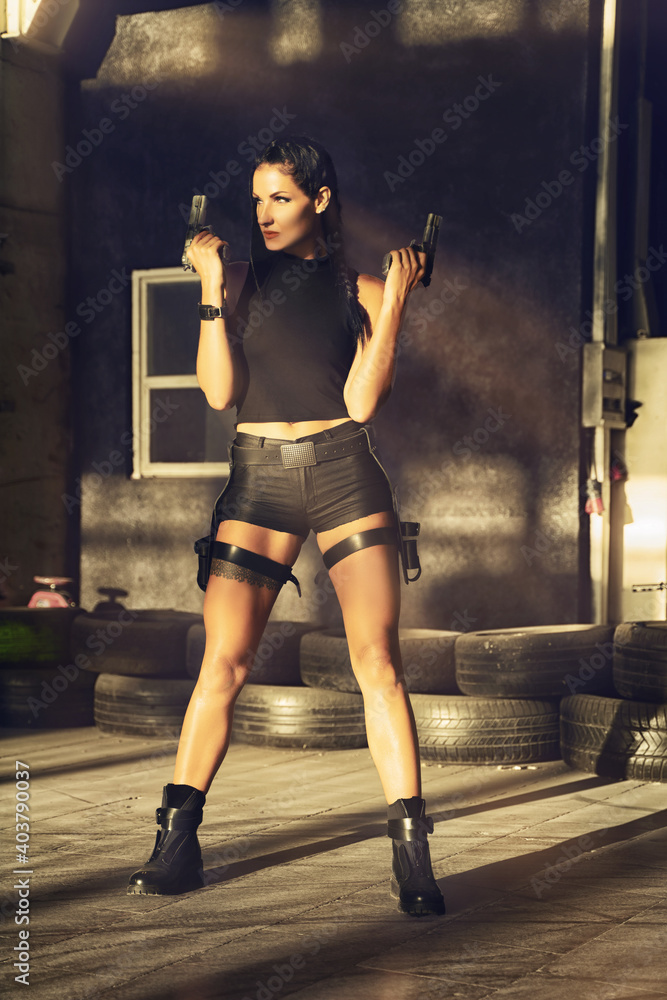 Lara Croft Tomb Raider action movie cosplay costume photoshoot with guns  and weapons brunette female model Stock Photo | Adobe Stock