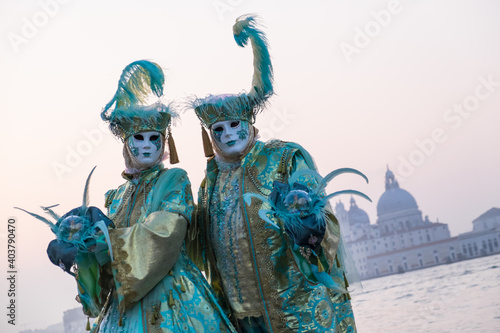 Venice, Italy - February 18, 2020: An unidentified couple in a carnival costume in front of Santa Maria della Salute, attends at the Carnival of Venice.