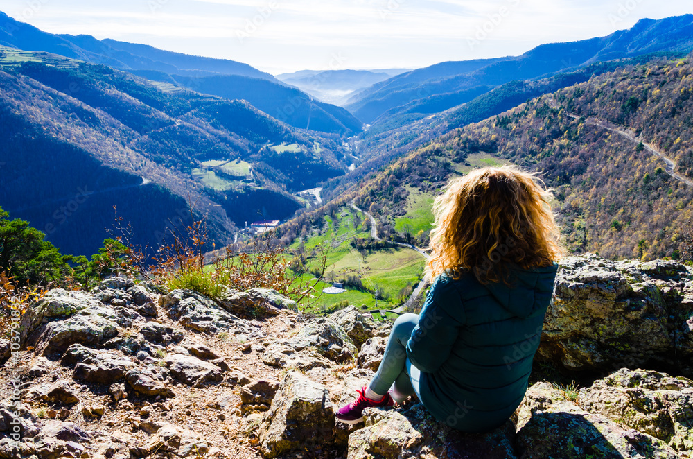Blond woman with curly hair, sitting on the mountain, looking at the fantastic views of the Ribes Valley, in the Ripolles region, Girona
