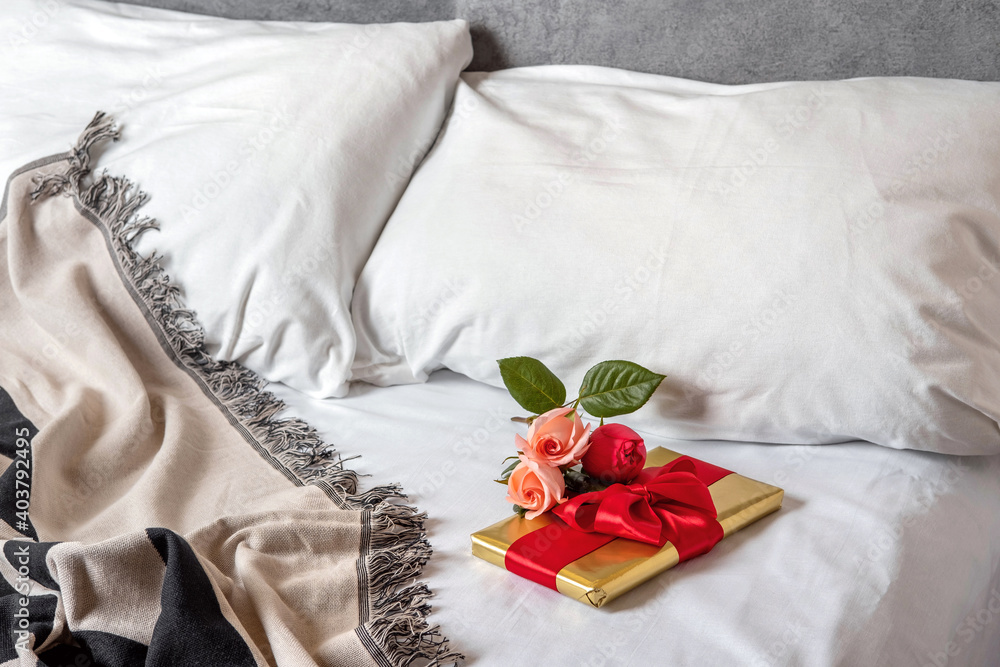 A gift box and flowers lies in bed early in the morning. Content for honeymooners and lovers for Valentine's Day. A gift box and flowers lies in bed early in the morning. Content for honeymooners and lovers for Valentine's Day.