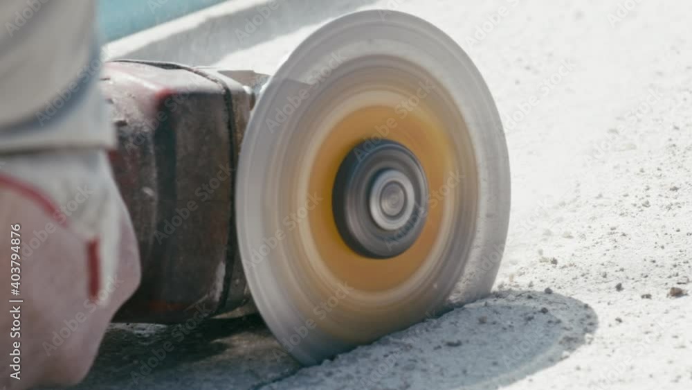 Cutting the concrete slab with electric circular saw. Construction worker cutting concrete floor and dust fly around, slow motion, close up Cutting the concrete slab with electric circular saw. Construction worker cutting concrete floor and dust fly around, slow motion, close up