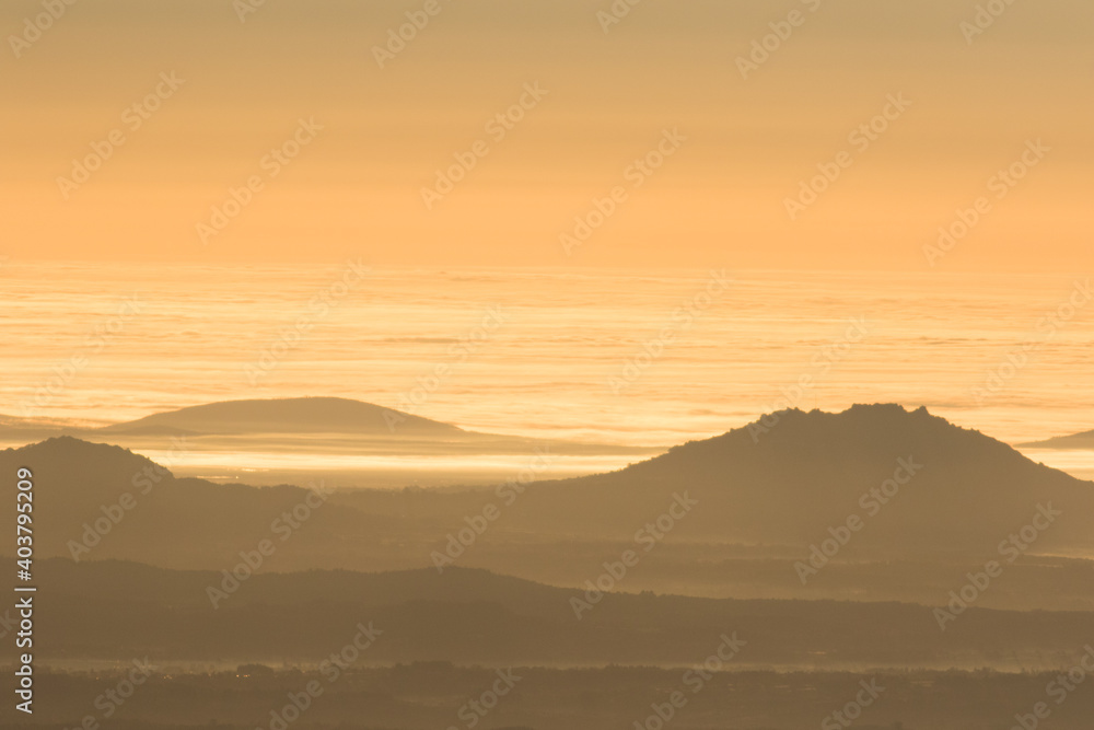 Winter in the Mountains. Beautiful orange mist or fog at sunrise time. Good sunlight and patterns in the landscape. Sea of clouds. Winter in the Mountains. Beautiful orange mist or fog at sunrise time. Good sunlight and patterns in the landscape. Sea of clouds.